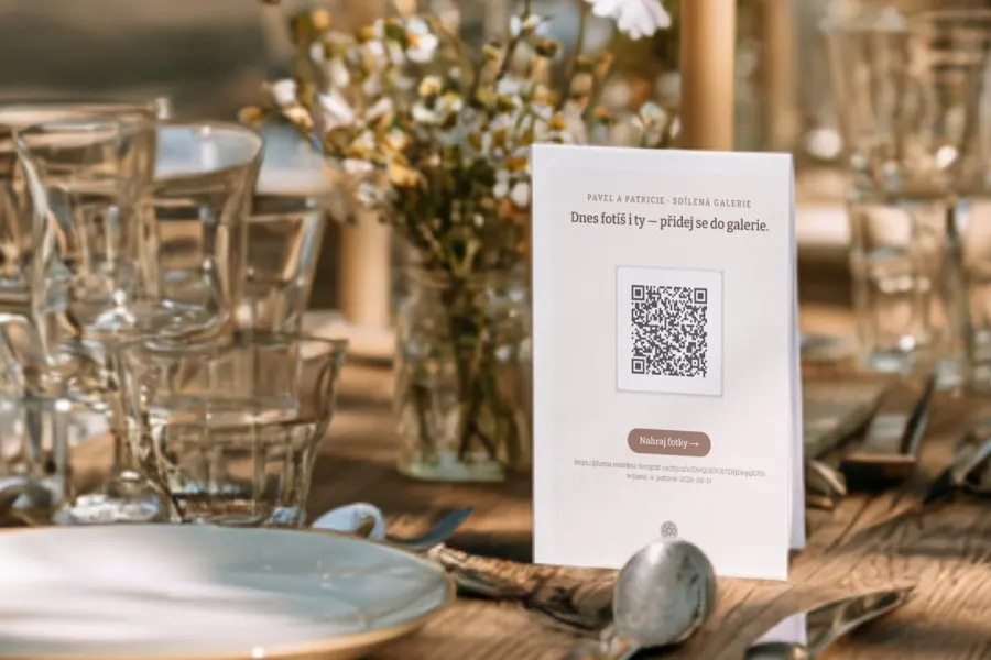 A table card with a QR code on the wedding table, among candles and place settings